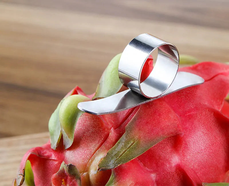 Silver stainless steel fruit peeler ring for oranges, citrus, and pomegranates on a kitchen surface.
