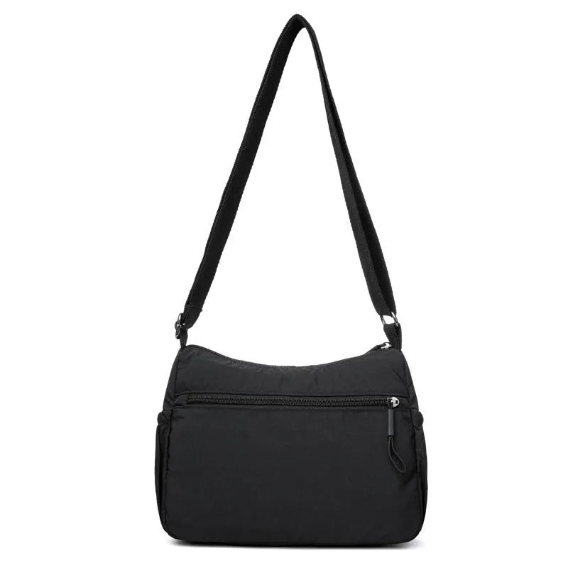 Soft grey nylon crossbody bag with an external pocket and adjustable shoulder strap.