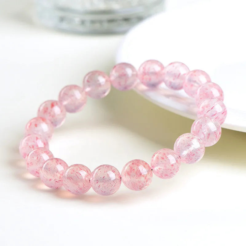Natural white water strawberry quartz geometric ball bracelet with 10-10.8mm beads on a wrist.