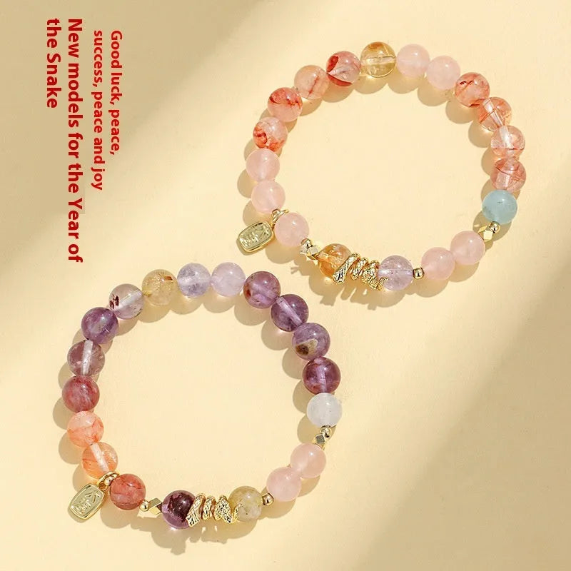 Handmade women's crystal string bracelet with lucky snake charm and coloured beads on wrist.