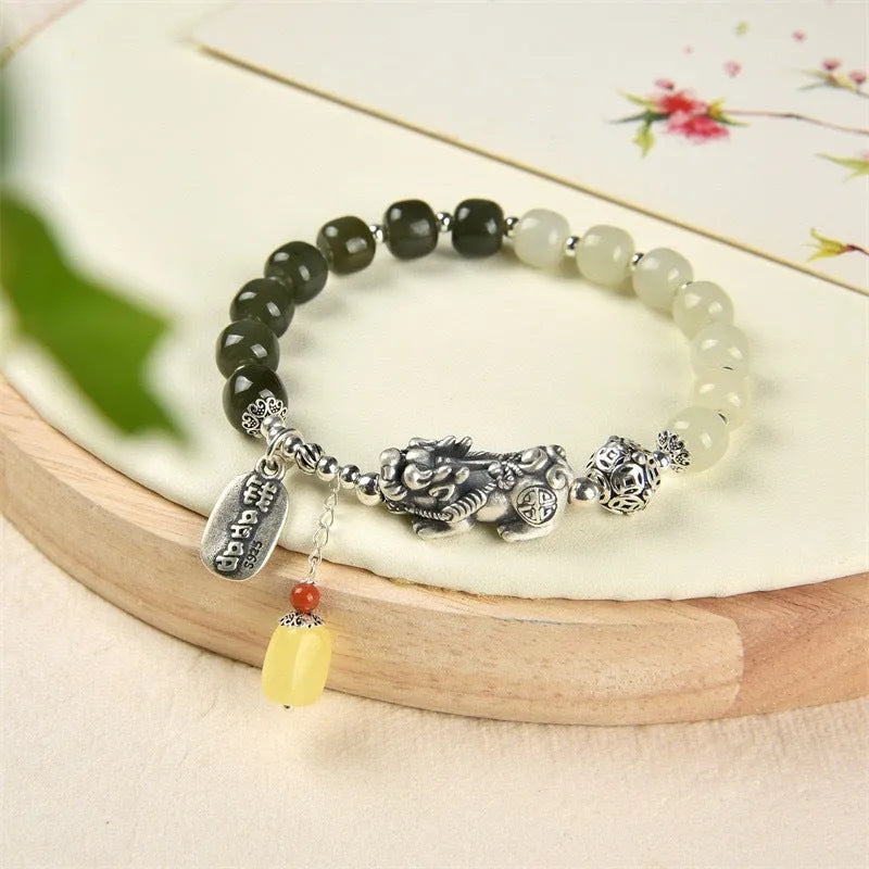 Handmade women's retro bracelet with a natural Hetian jade bead and pure silver coin charm on an adjustable chain.