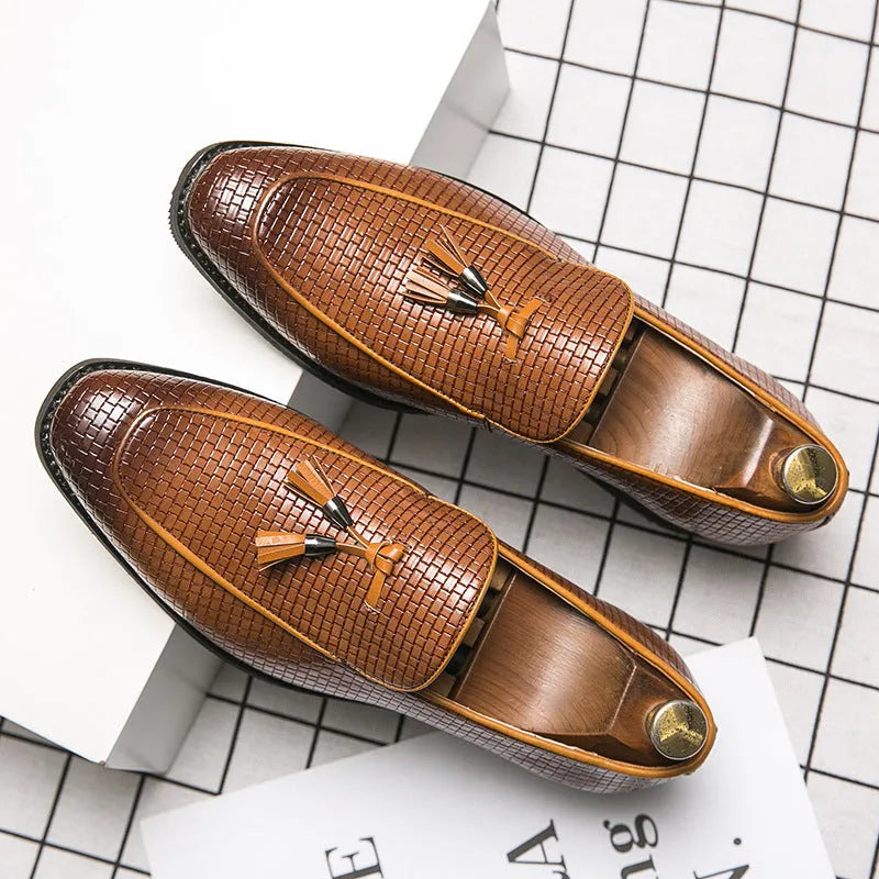 Men's black pointed slip-on business shoes with a tassel detail on the artificial PU leather upper.