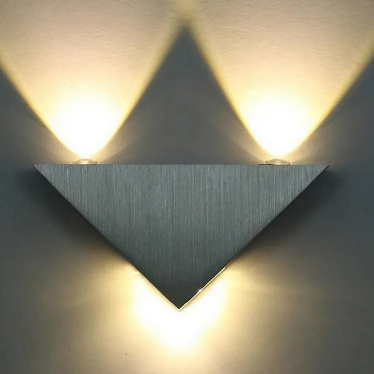 Set of three white LED wall lights with dual heads mounted on a wall showing warm white light