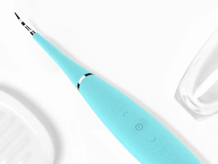 Pink and blue electric dental scaler tool with silicone handle on a bathroom counter.