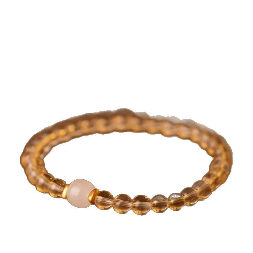Close-up of a rutilated quartz bracelet showing gold rutile needles within green stone beads.