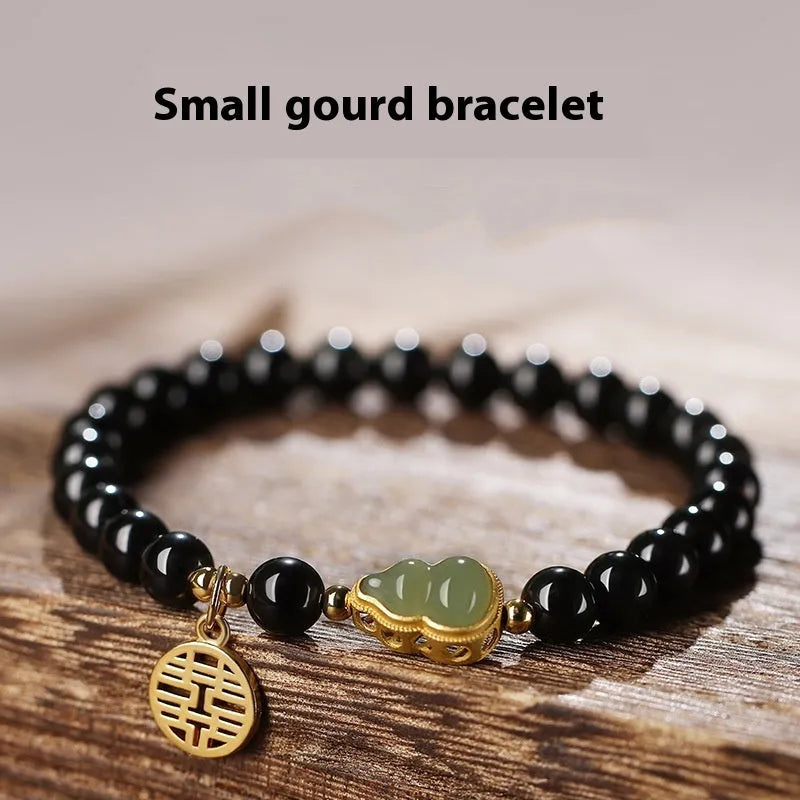 Black obsidian bracelet with carved Hetian jade gourd charm showing geometric patterns