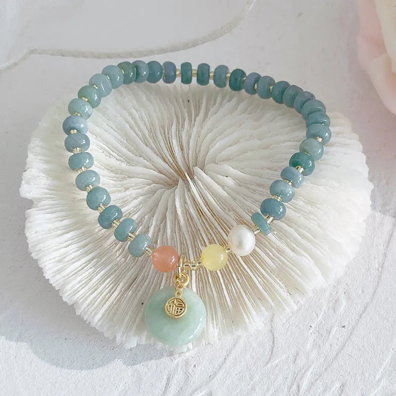 Women's jade bracelet with gourd shape, peace buckle charm, and strawberry quartz details in natural blue colours