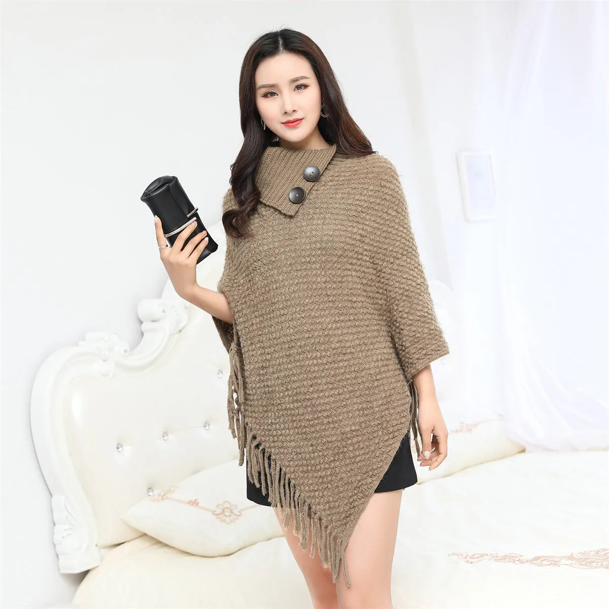 Dot-patterned acrylic knitted shawl cloak in apricot colour, laid flat.