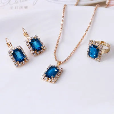 Crystal bridal three piece jewellery set with alloy setting, artificial gems, adjustable chain necklace, earrings, and ring on white background
