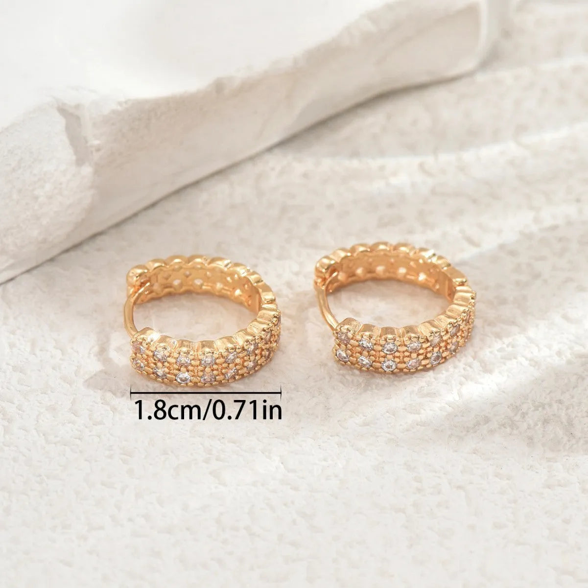 A pair of copper geometry pattern ear studs with round, dot, and ring design elements.