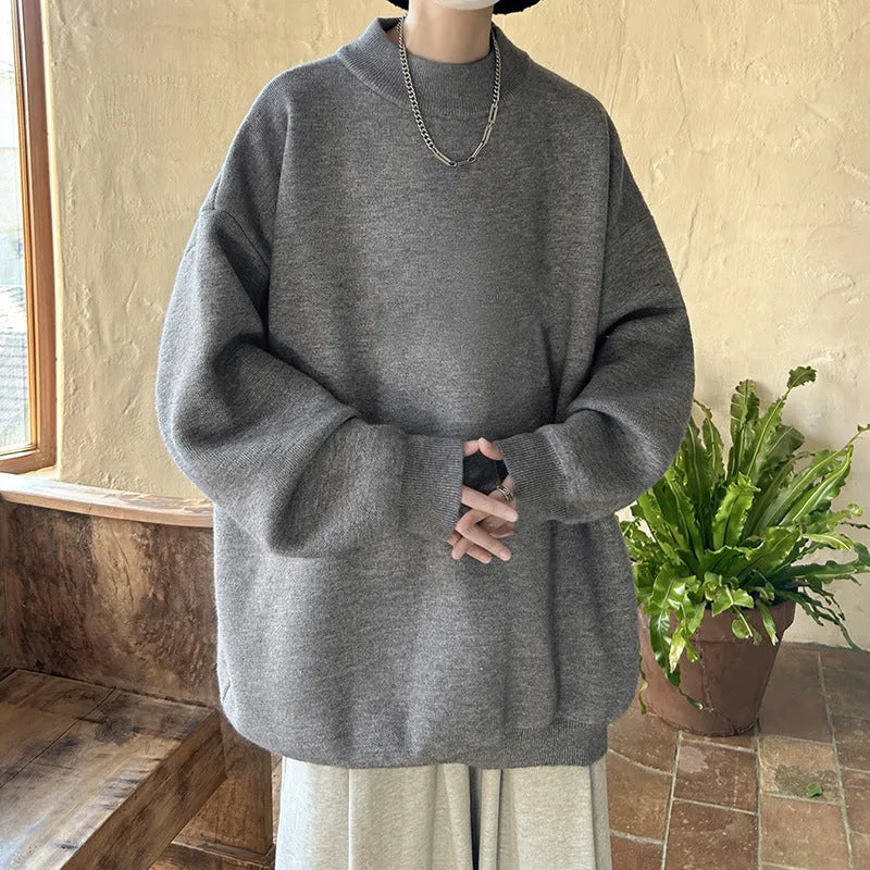 Man wearing a loose fit, solid colour round neck pullover sweater.