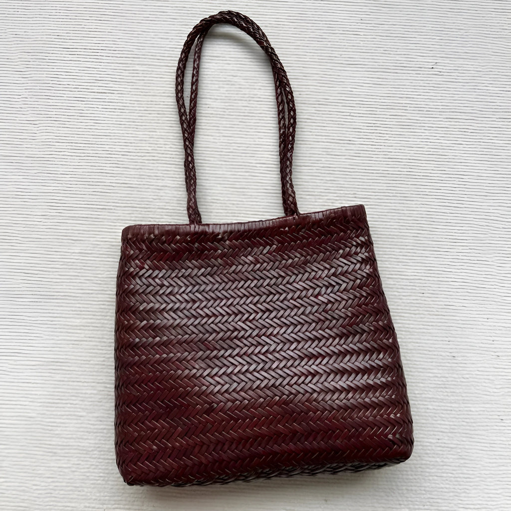 Brown handmade woven cowhide leather tote bag with a three-dimensional front pocket.