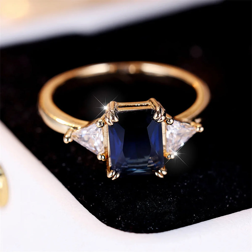Women's rectangular copper ring in gold sapphire blue on a neutral background, showing its geometric band shape.