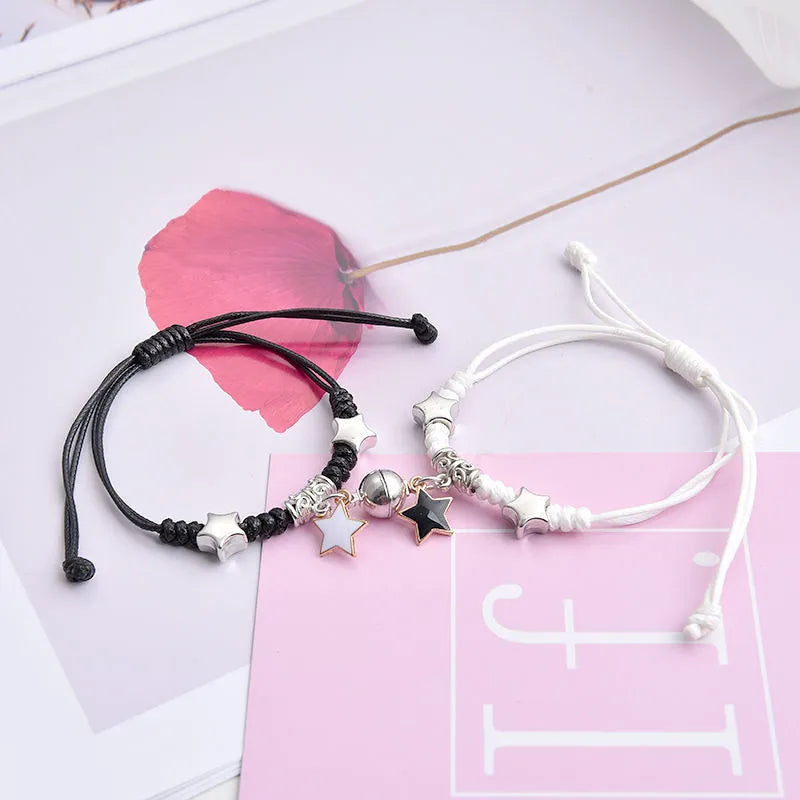A pair of magnetic couple bracelets with alloy charms showing an I love you design and a key lock on a textured background.