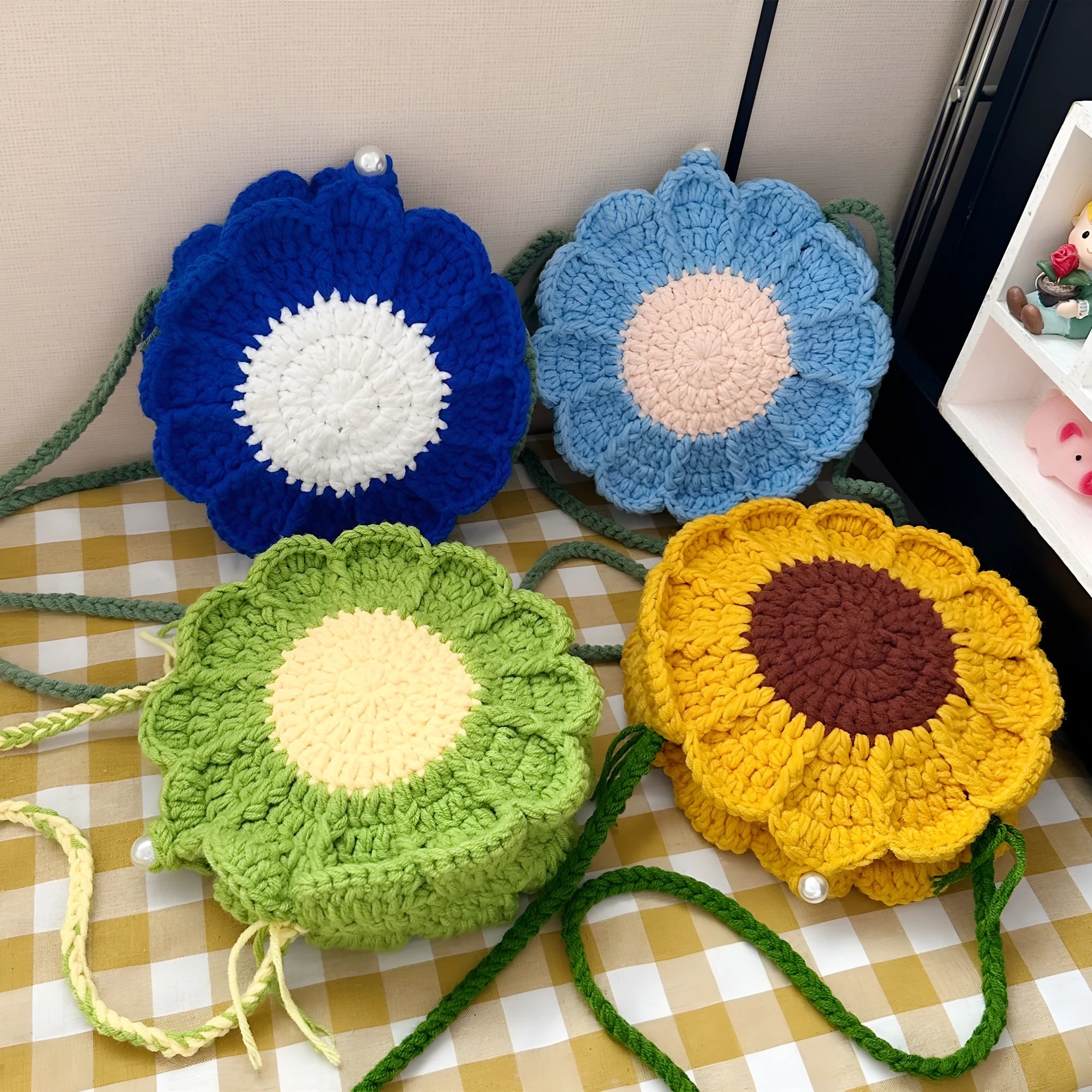 Hand-woven wool crochet bag with flower detailing and round suitcase shape showing internal mobile phone pocket