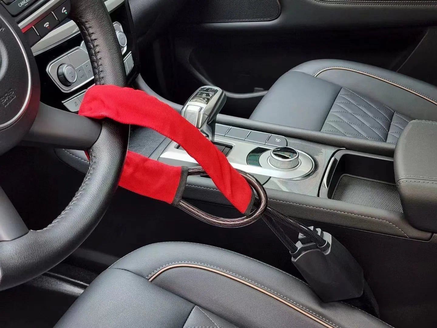 Red iron car steering wheel lock with wire rope, shown on a GM vehicle steering wheel.