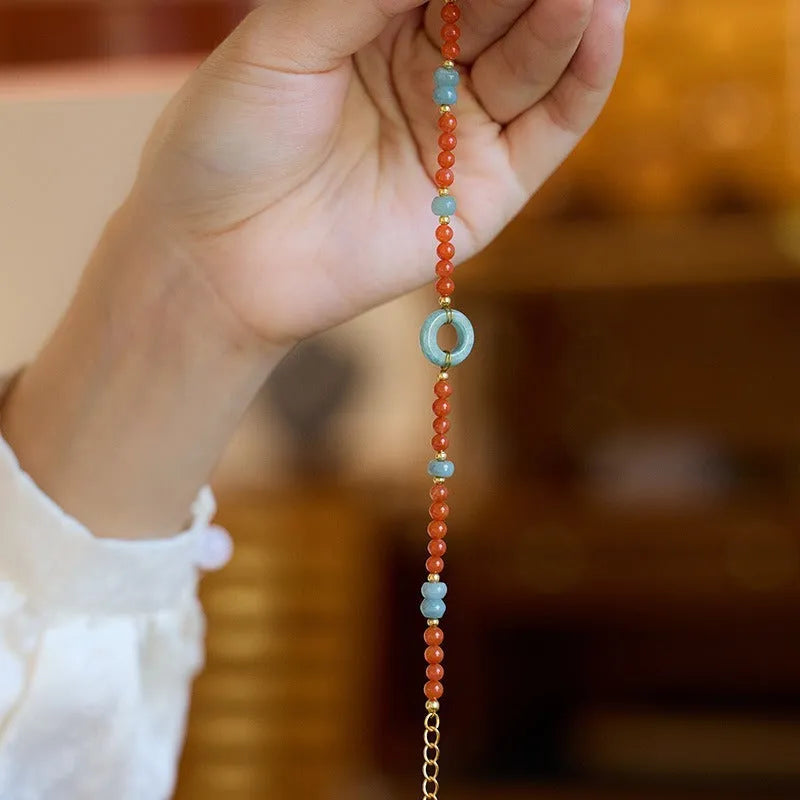 Close-up of a women's south red agate bracelet with geometric beads and a safety buckle clasp on a wrist.