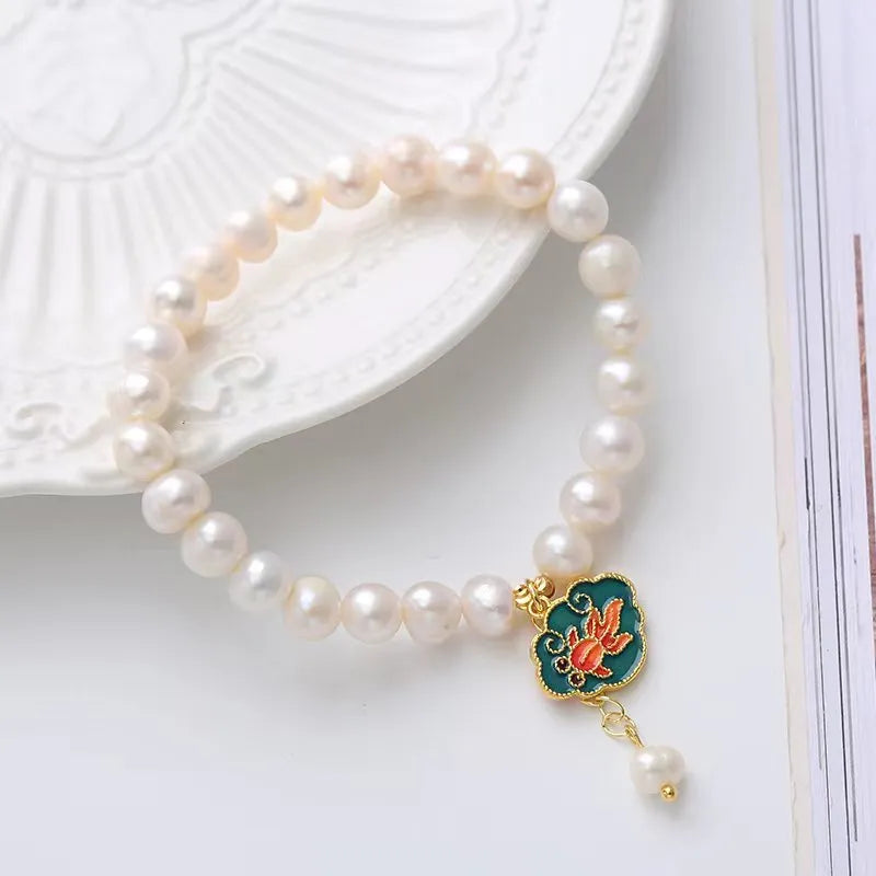White antique freshwater pearl bracelet with a vintage goldfish and baroque lotus pendant on a chain.