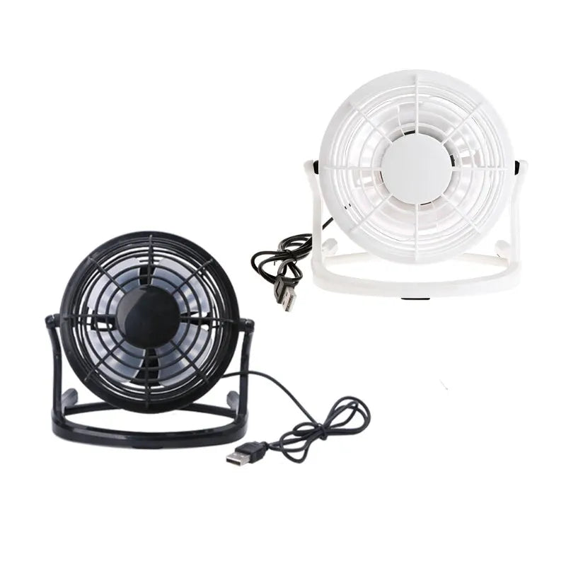 Mini black USB desk fan with adjustable tilt angle on a wooden desk next to a laptop.