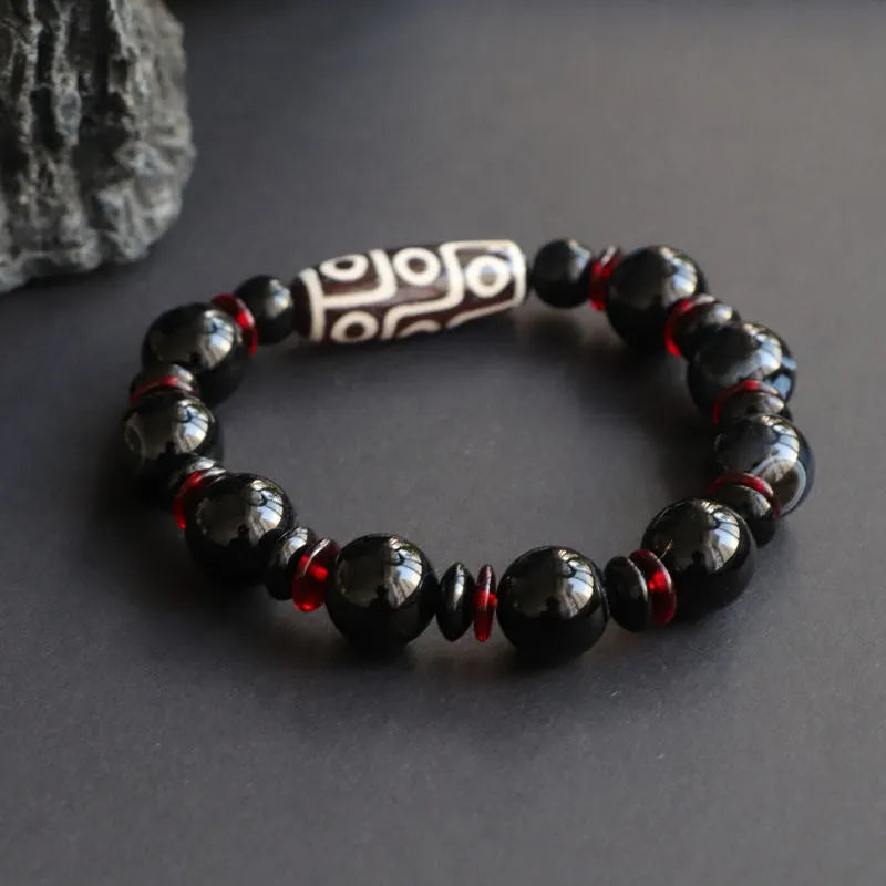 Black agate dzi bead bracelet with hand-woven geometry beads on a wrist.