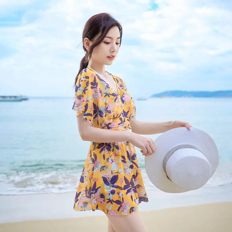 Yellow women's one-piece swimsuit with a floral pattern, shown on a hanger.