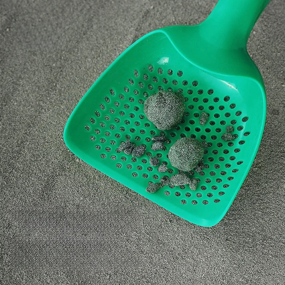 Green plastic cat litter scoop with hollow head and handle on white background
