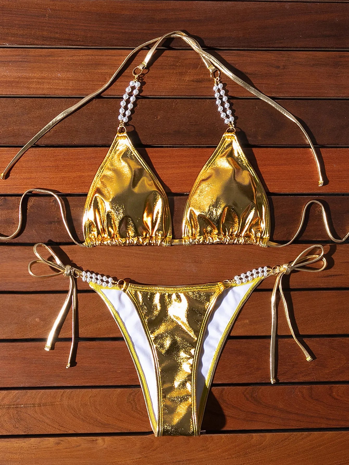 Gold halter neck bikini top with lace-up front and matching briefs, featuring pearl chain detail.