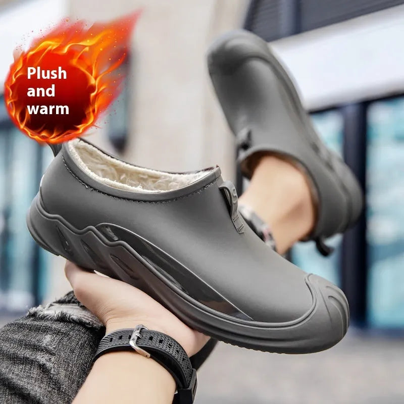 Men's black plastic rain boots on a grey background showing ankle height and solid colour design.