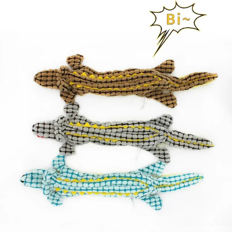 Blue plush crocodile-shaped dog toy with corduroy texture and squeaker, shown next to measuring tape