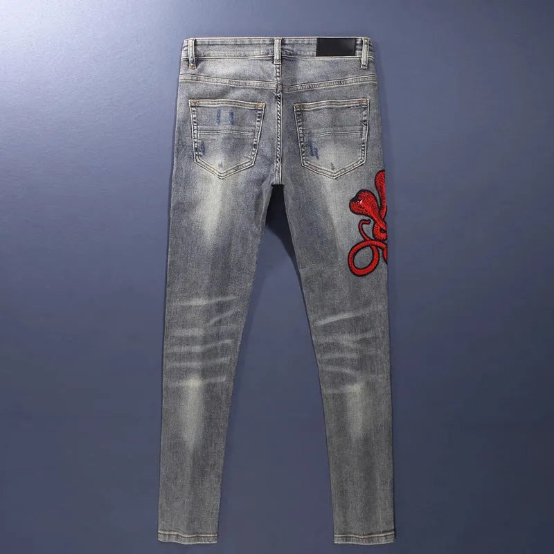 Men's slim fit vintage jeans with a washed-out colour and distressed hole patch embroidery.