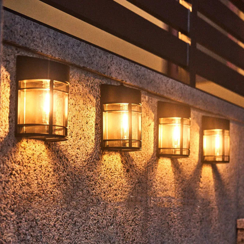 Small white solar-powered outdoor wall light with a dark solar panel on top, mounted on a wall.