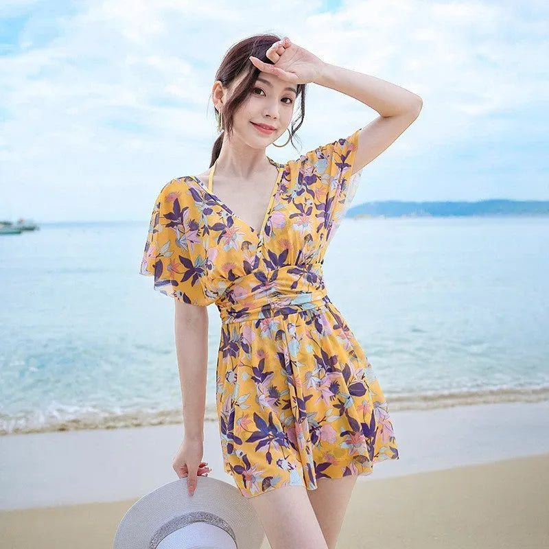 Yellow women's one-piece swimsuit with a floral pattern, shown on a hanger.