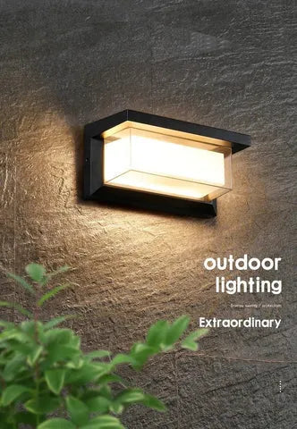 Waterproof IP65-rated outdoor wall lamp with aluminium body and acrylic shade, shown in a garden setting.
