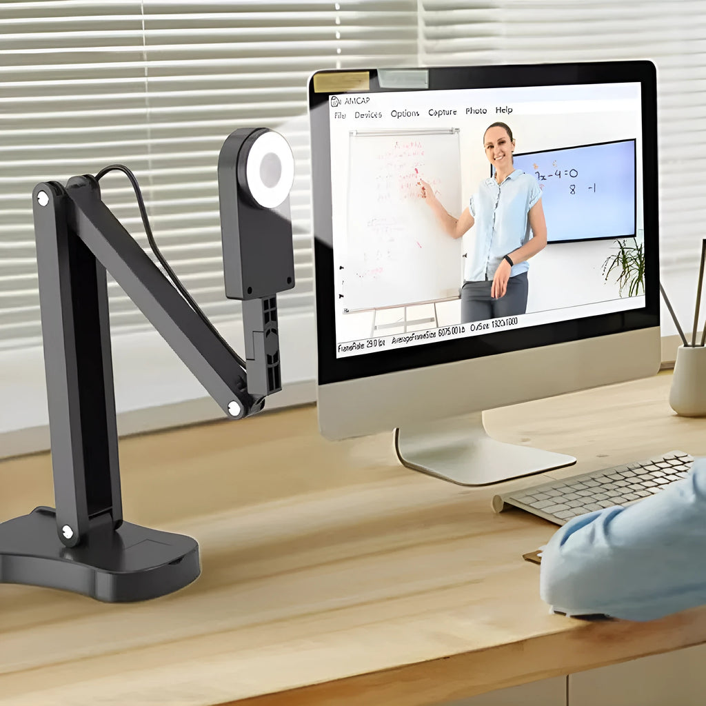 USB computer webcam with built-in microphone on a desk next to a monitor