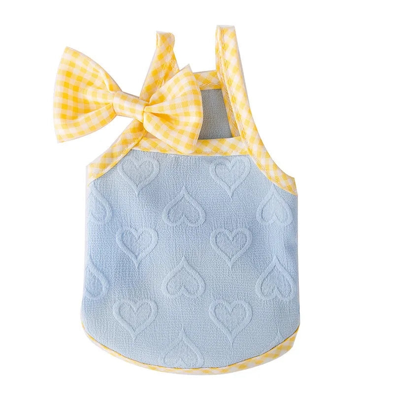 Small dog wearing a blue elastic vest with bow suspenders and a raised heart texture design.