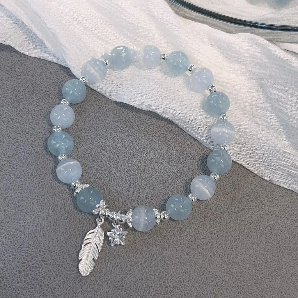 Korean style blue crystal bracelet with white lettering and a star charm on a wrist.