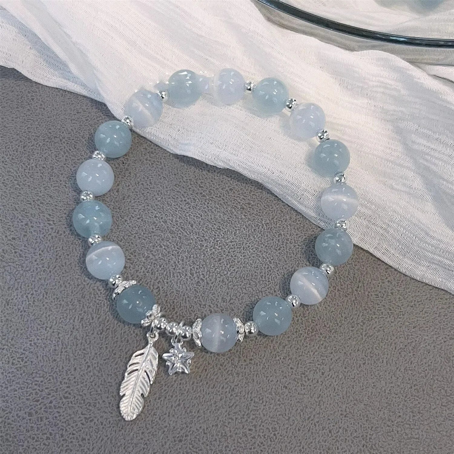 Korean style blue crystal bracelet with white lettering and a star charm on a wrist.