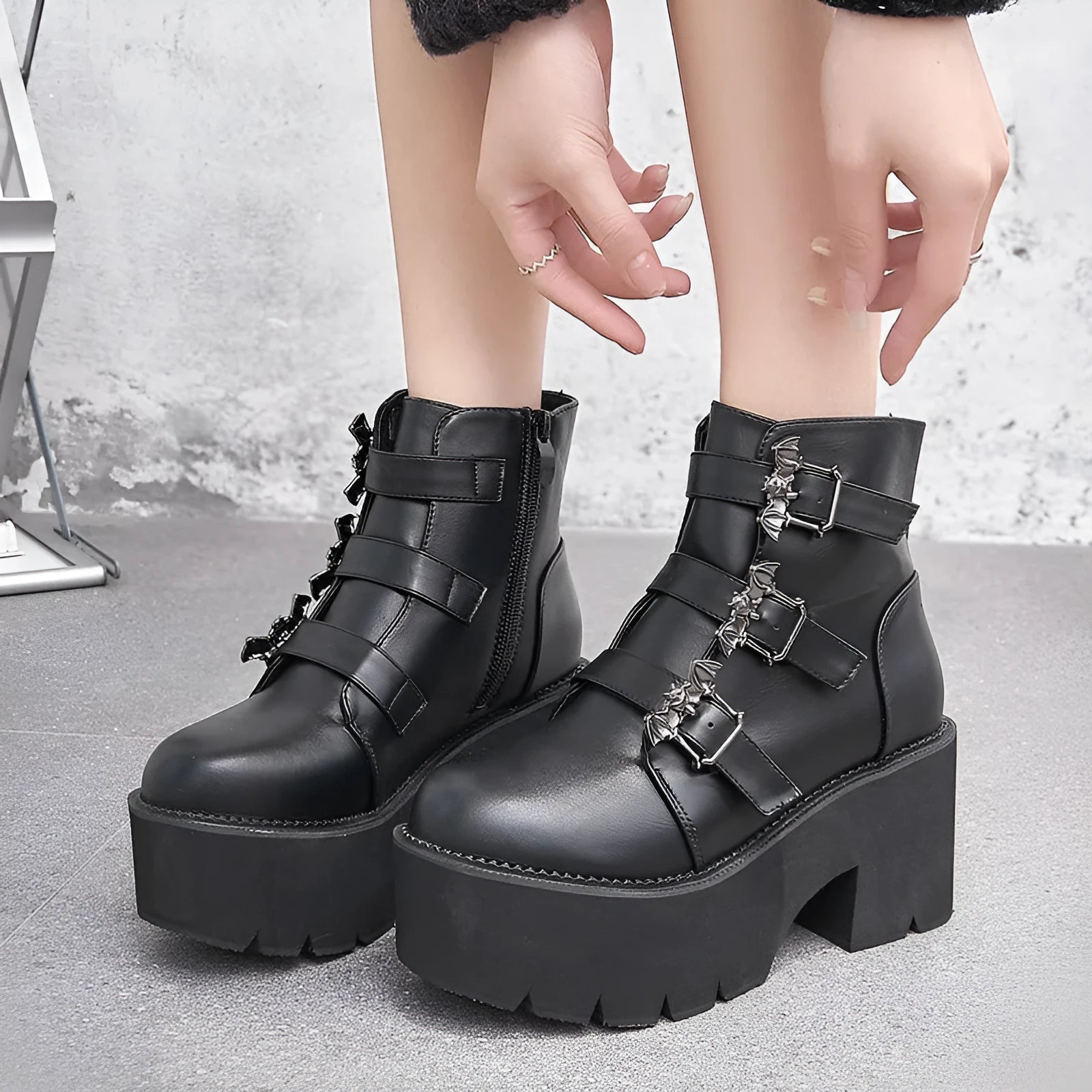 Black women's punk ankle boots with bat buckle and side zip on a thick sole.
