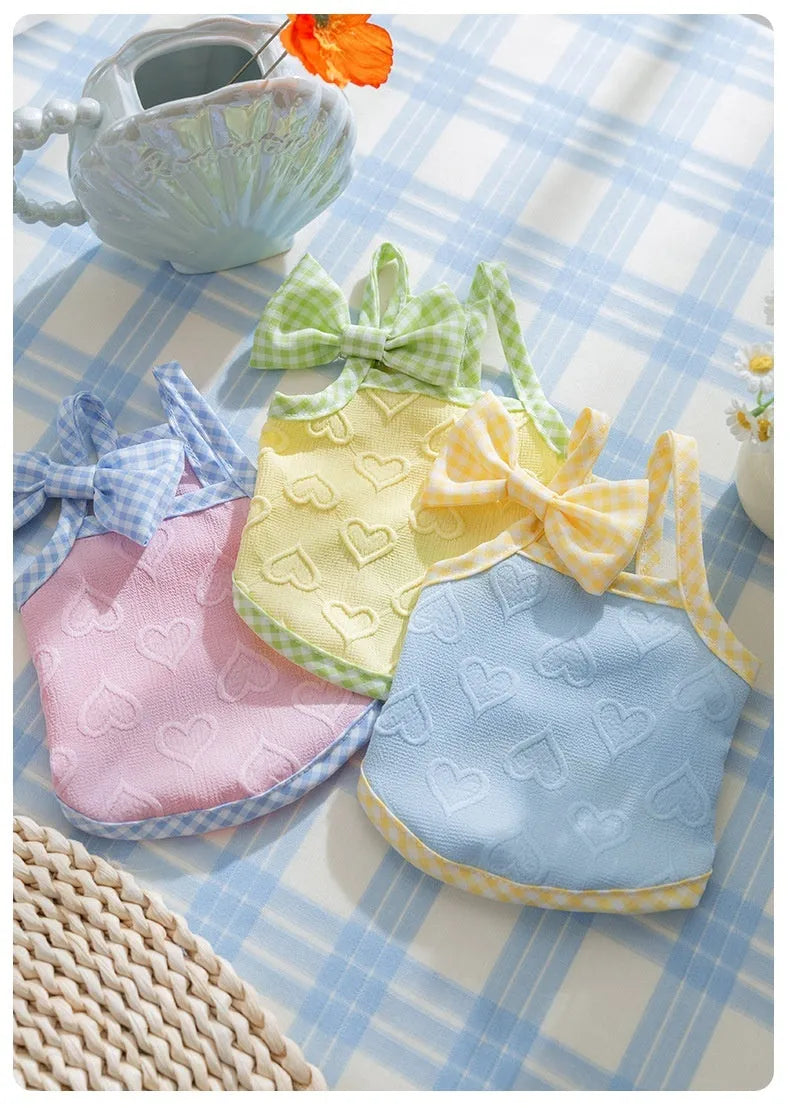 Small dog wearing a blue elastic vest with bow suspenders and a raised heart texture design.