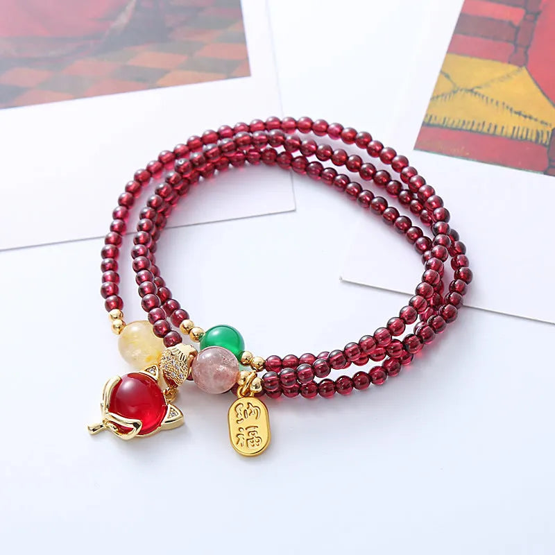 Purplish red garnet fox charm on an adjustable rope bracelet for women.