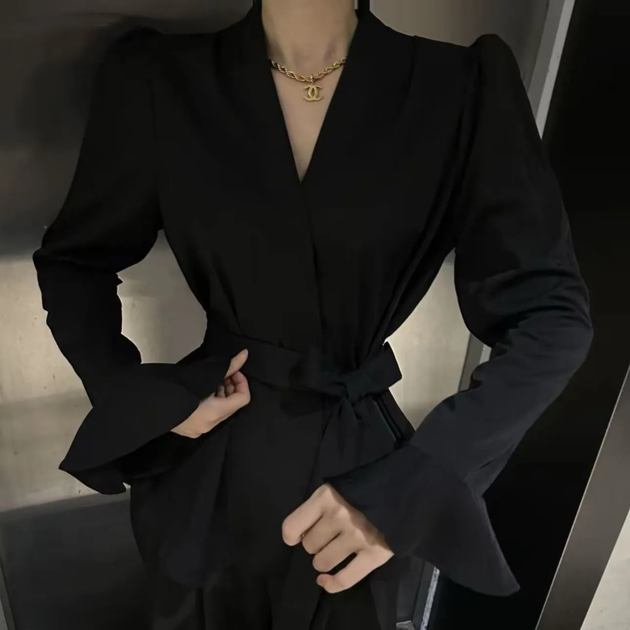 Women's black French-style shirt with irregular collar, long bell sleeves, and a tied front.