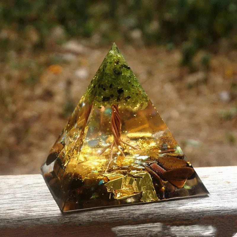 Small 6cm high clear epoxy resin pyramid ornament filled with colourful natural crystal gravel on a shelf.