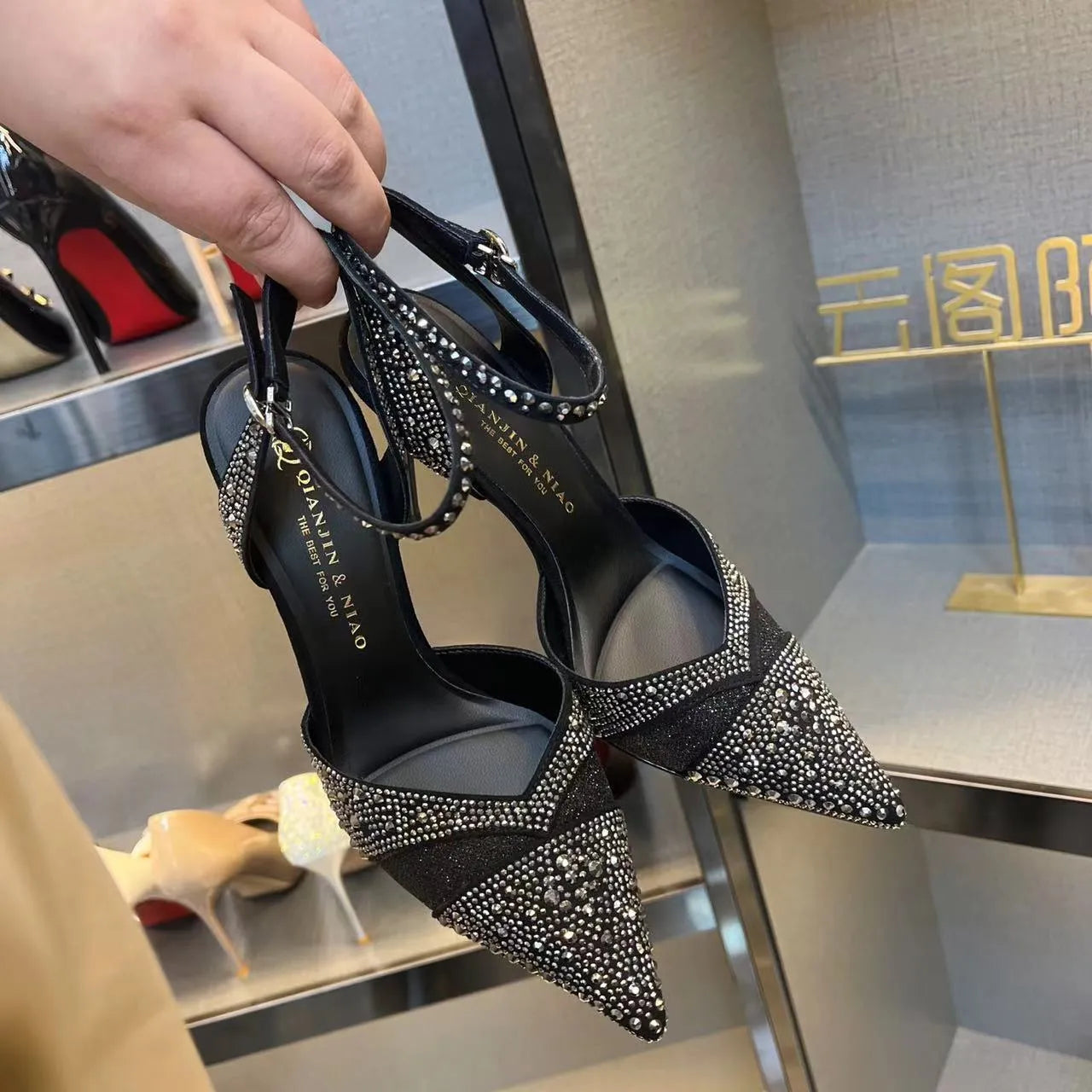 Women's black and silver hollow high heels with a red sole and pointed stiletto toe.
