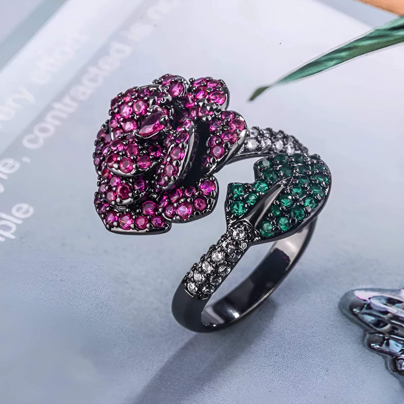 Geometric black gold plated ring with red simulated corundum stone in a floral setting.