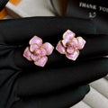 Close-up of a pair of gold plated flower stud earrings with a purple oil-spot glaze finish.