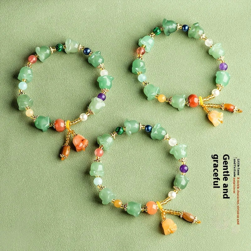 Close-up of a carved orchid bead jade bracelet in aventurine orchid colour on a wrist.
