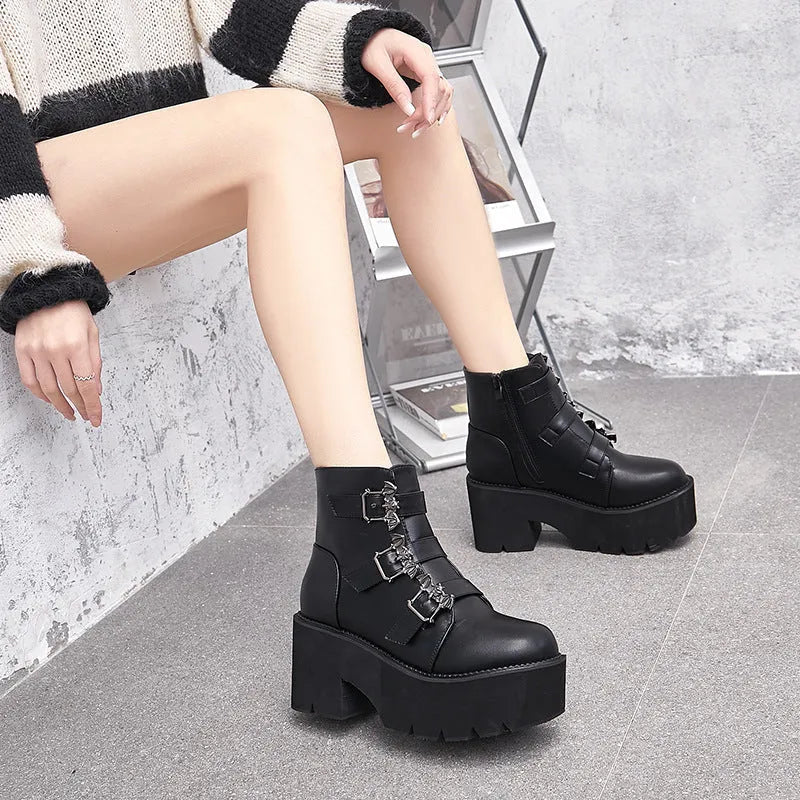 Black women's punk ankle boots with bat buckle and side zip on a thick sole.