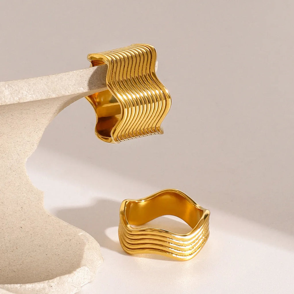 Stainless steel ring with a geometric wave pattern on a wide band, showing two colour options.
