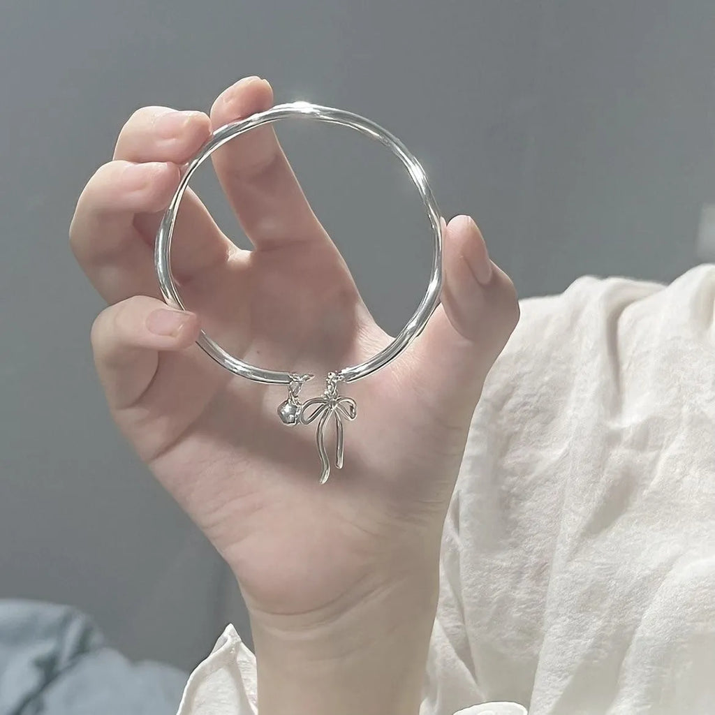 Silver adjustable bracelet with a detailed bow charm clasp on a white background.