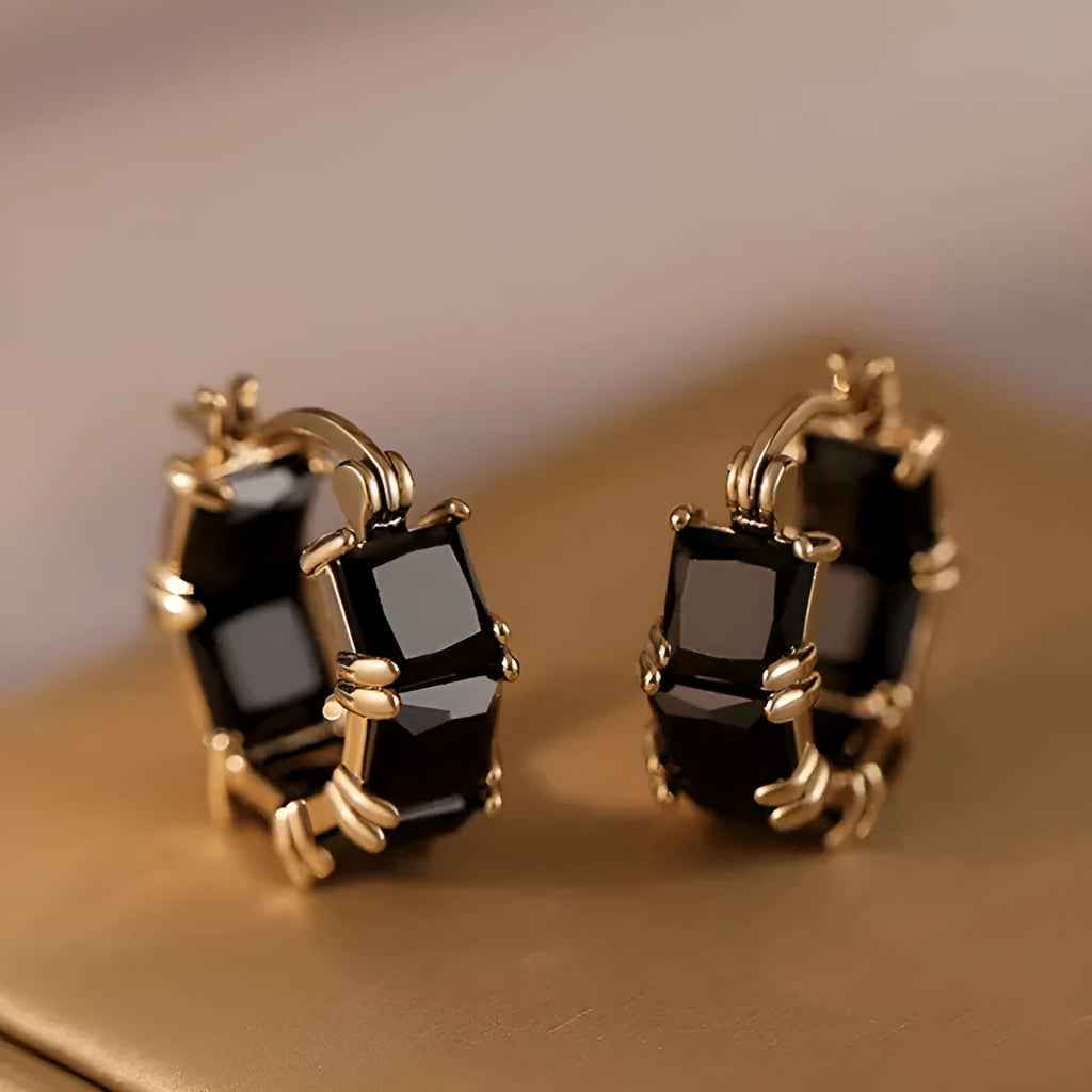 Geometric gold U-shaped hoop earrings with a round black zircon stone, shown from a side view.
